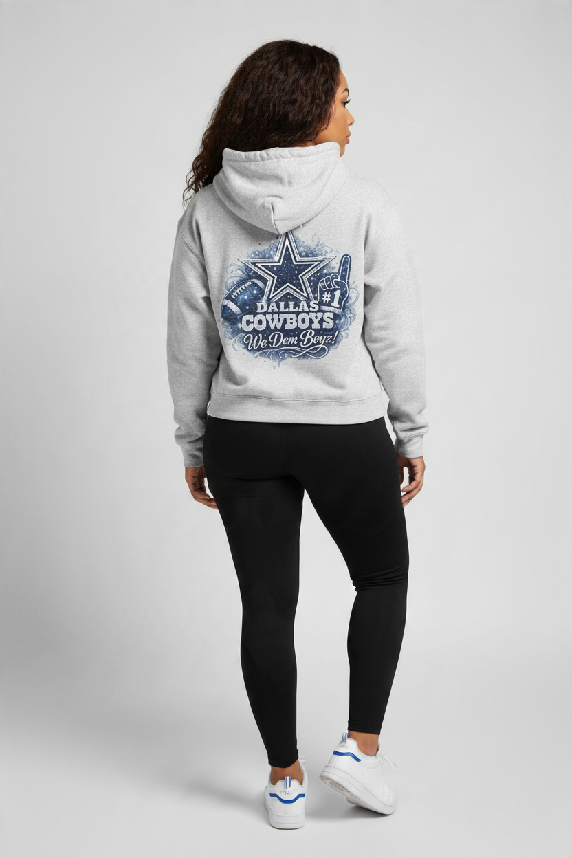 A woman shown from the back wearing a light gray hoodie with a large distressed blue Dallas Cowboys 'We Dem Boyz' graphic on the back, paired with black leggings and white sneakers, against a light gray studio background.